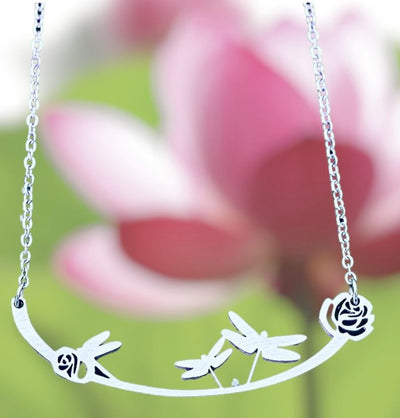 Three dragonflies and two flowers make up this Dragonflies Stainless Steel Necklace on Harvest Array
