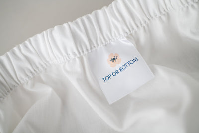 Fitted white cotton sheet showing American Blossom Linens tag for either the Top or Bottom of the bed.