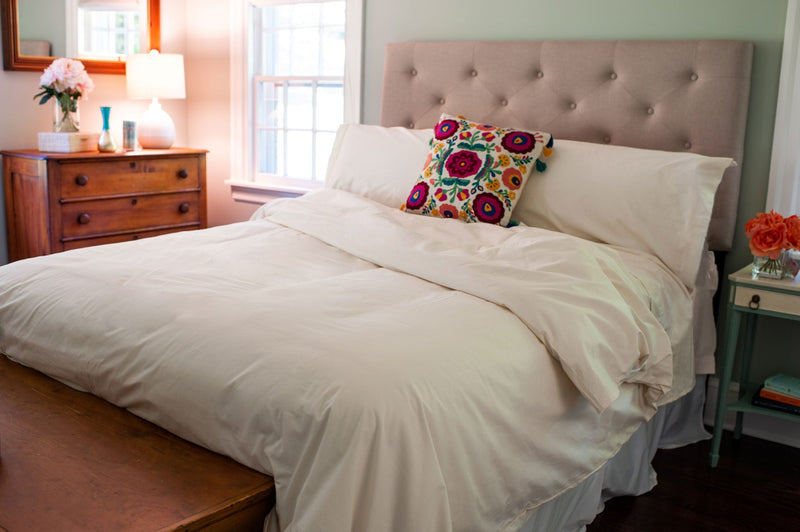 Organic cotton duvet cover set and pillow shams in natural color look beautiful and cozy on this freshly made bed in an earth tone bedroom.