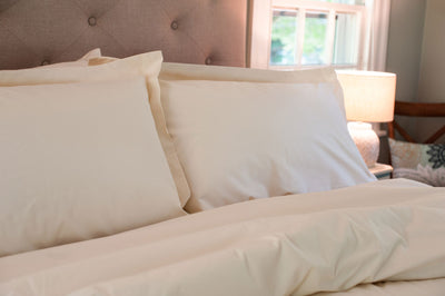 Upgrade your bed with our soft Organic cotton pillow shams with pillows on a made bed in natural color.