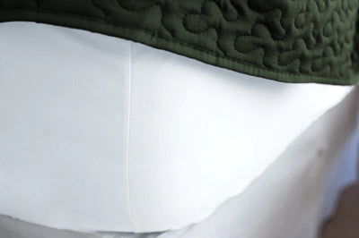 Corner of white American Blossom Lines cotton fitted sheet shows the deep 16" pocket giving a tight fit around the mattress. 