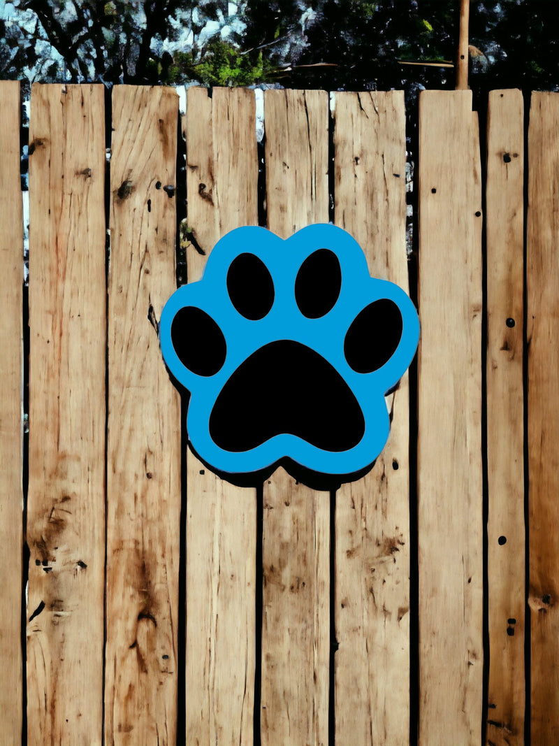 Sky Blue /Black Wooden Paw Print Door Hanger displayed on a backyard fence.