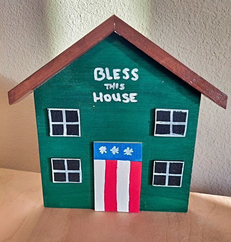 House shaped handmade plaque with American flag door and "Bless This House" hand painted  above it.