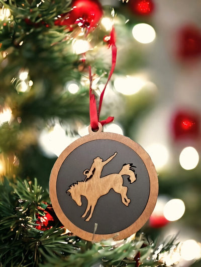 Round wooden Christmas ornament with a n engraved picture of a horse with a rodeo rider on its back.