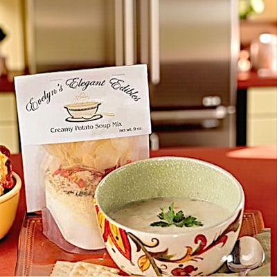 Bag of Evelyn's Elegant Edibles creamy potato soup mix next to a bowl of soup on a kitchen counter.