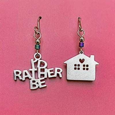 One Earring says "I'D RATHER BE " the other earring is a house shape.