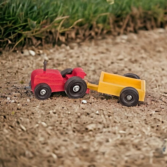 Amish made small red tractor with yellow wagon toy, out on the farm.