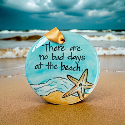 Decorative ornament with a starfish and 'There are no bad days at the beach' on a beach background. Made in the USA for Harvest Array.