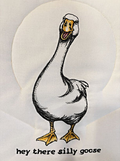Close up of the embroidered silly goose and saying.