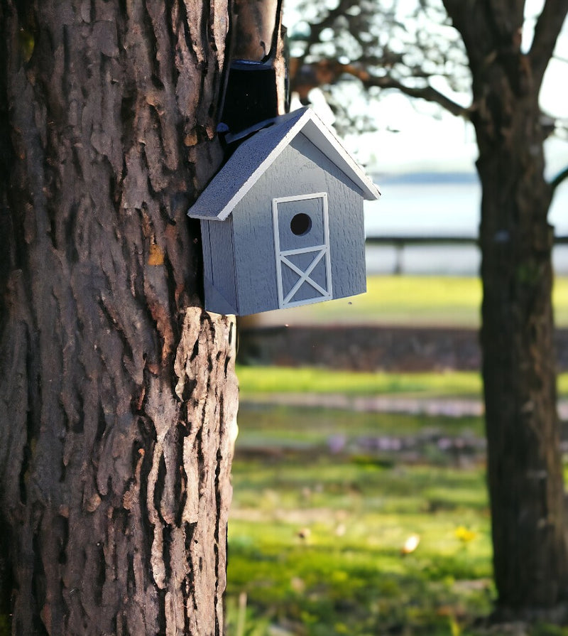 A blue wooden birdhouse mounted to a tree