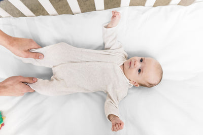 Baby laying face up in American Blossom Linens organic crib sheet, now available at harvestarray.com.