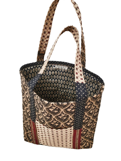 This quilted tote is comprised of several fabrics in brown and navy coordinating patters on the inside and outside. 