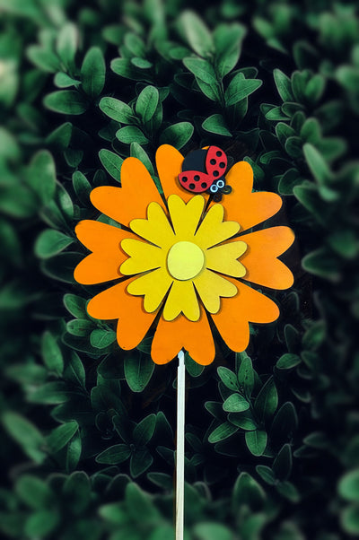 Orange and yellow daisy garden stake in the garden